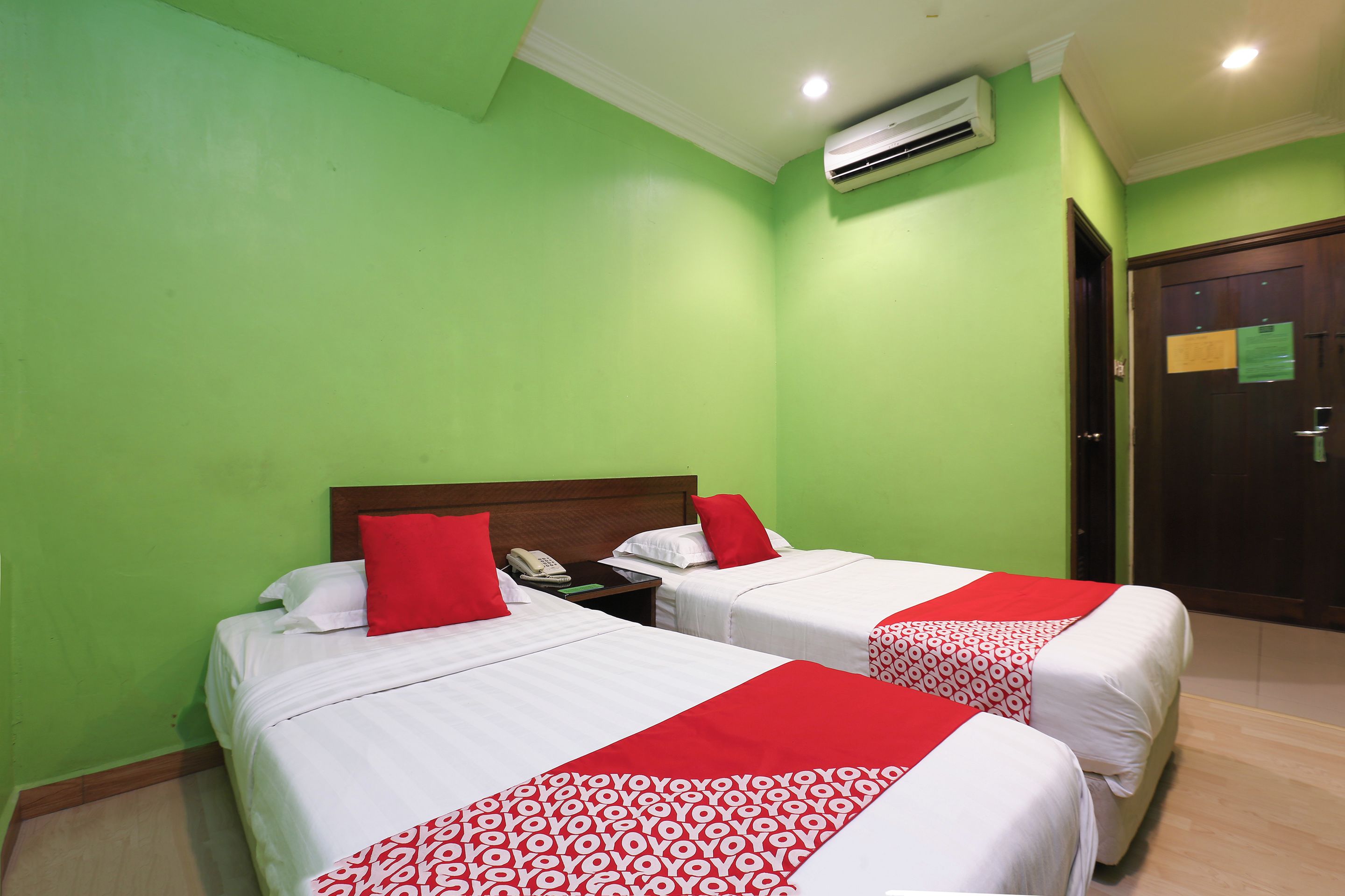 A hotel room with two beds, a telephone, and an air conditioning unit.