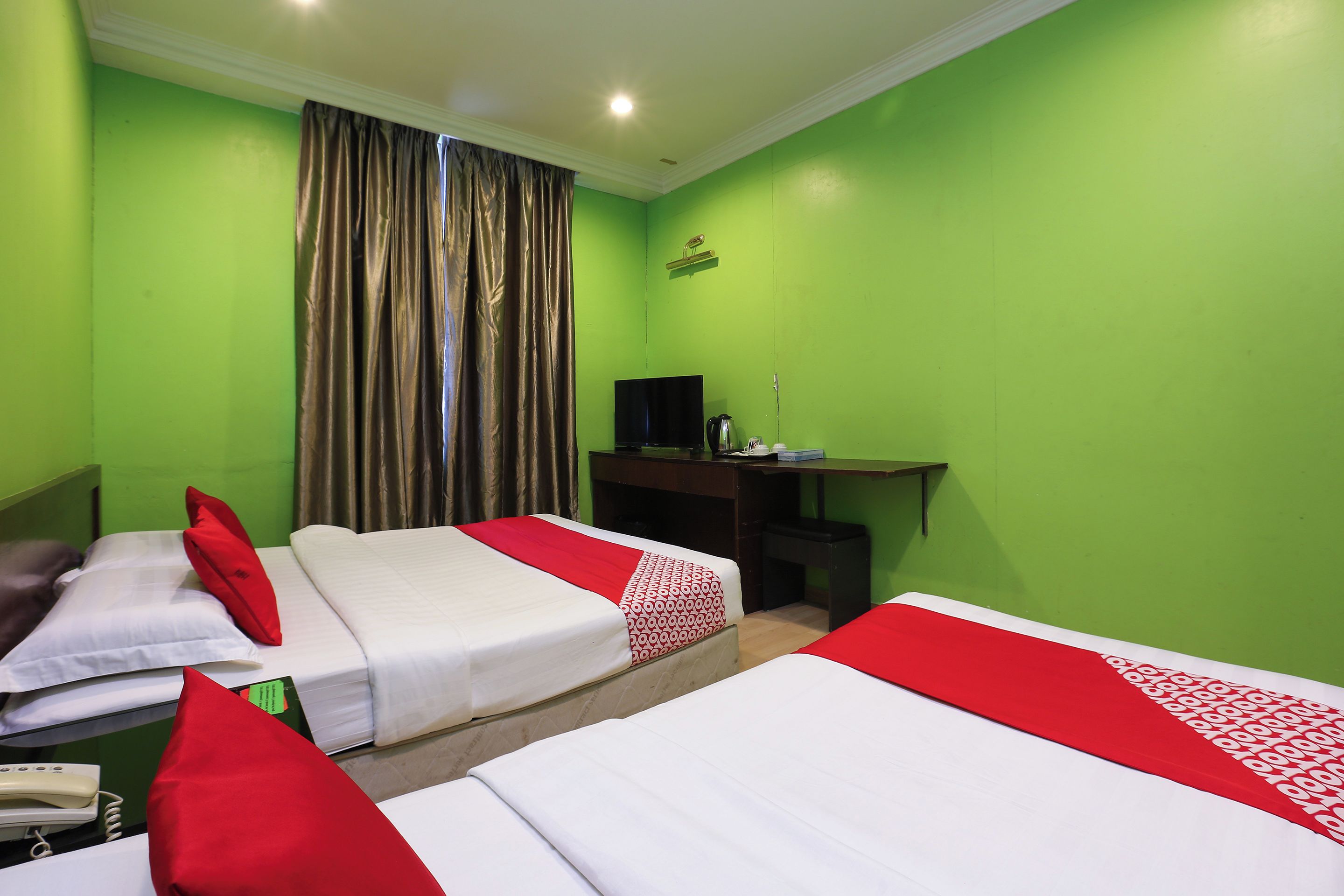 A hotel room with two beds, a desk, a television, and a telephone.