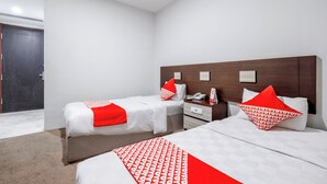 Ein Hotelzimmer mit zwei Betten, einem Holzkopfende, einem Nachttisch mit Telefon und einer Tür.