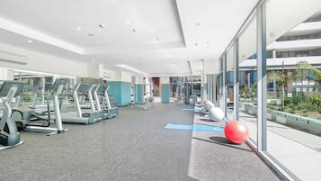 A modern gym with treadmills, exercise balls, and a glass wall offering a view of the outside.