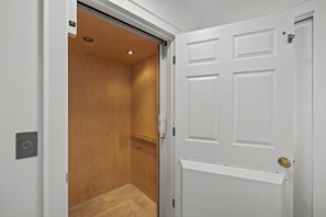 A white door with a gold handle, a white panel with a 'call' button, and a wooden door frame. - Seabiscuit-Oceanfront Home with Private Pool (Atlantic Beach)