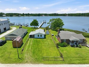 A lakeside property with a dock, a grassy yard, and several buildings. - Marshallberg Waterfront Cottage w/Dock! (Marshallberg)