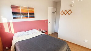 A bedroom with a bed, a nightstand, a wall-mounted lamp, and a door. - Loft Campeche 500mt da Praia - Floripa (Florianópolis)