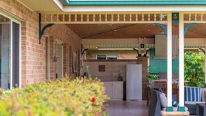Un espacio exterior techado con cocina, asientos y una pared de ladrillo.