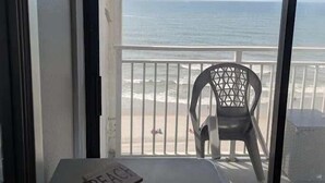 A balcony with a view of the beach, a chair, and a table with a magazine. - Sea Mist 20907 Newly Renovated Oceanfront Studio (Myrtle Beach)