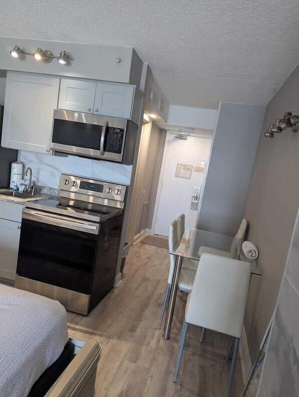 Una cocina compacta con microondas, horno y un pequeño comedor con mesa y sillas.