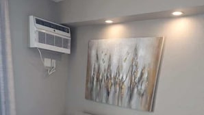 A modern living room with a grey sofa, a glass coffee table, and a wall-mounted air conditioner. - Sea Mist 20907 Newly Renovated Oceanfront Studio (Myrtle Beach)