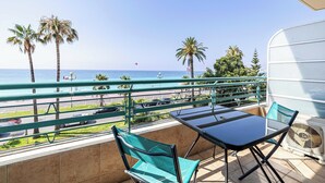 A balcony with a view of the sea, a table, chairs, and a fan. - Charming Apartment a/c 2P by the Seafront - Nice (Nice)