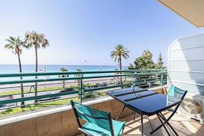 Ein Balkon mit Meerblick, einem Tisch, Stühlen und einem Ventilator.