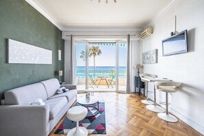 Ein modernes Wohnzimmer mit einer Couch, einem Couchtisch und Blick auf den Strand durch die Glastür.