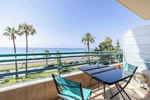 Ein Balkon mit Meerblick, einem Tisch, Stühlen und einem Ventilator.