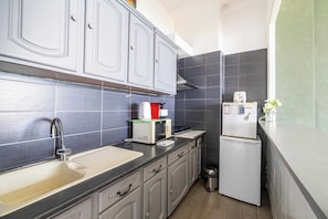 A compact kitchen with grey cabinets, a stainless steel sink, a toaster, a kettle, and a small refrigerator. - Charming Apartment a/c 2P by the Seafront - Nice (Nice)