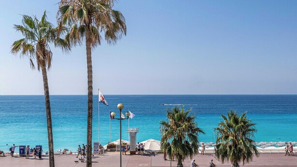 A coastal promenade with palm trees, a clear blue sea, and a few people walking. - Charming Apartment a/c 2P by the Seafront - Nice (Nice)