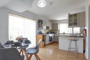 Eine moderne Küche mit Essbereich, Holzboden und einem Barhocker.