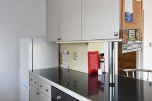 Una cocina equipada con refrigerador, armarios, una manta ignífuga y un extintor.