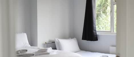 Habitación de hotel con dos camas, una ventana con cortina negra y un candelabro.