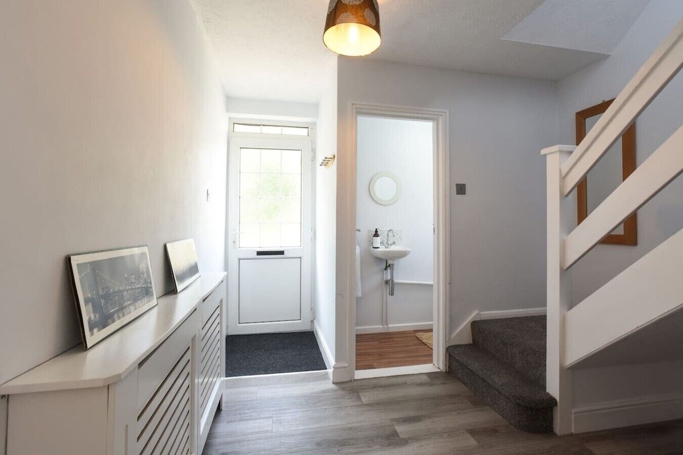 A hallway with a white door, a small sink, and a staircase.