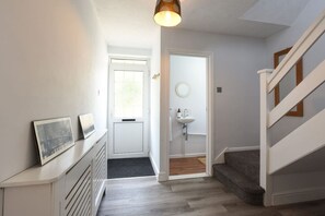 A hallway with a white door, a small sink, and a staircase. - Spacious 4-Bedrooms and 6 Beds Home | Free Parking | Ideal for Contractors & Families (Hampshire)
