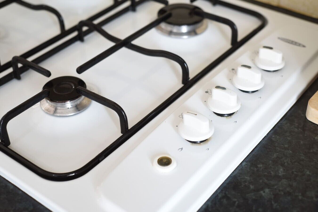 Een gasfornuis met vier branders en vier knoppen.