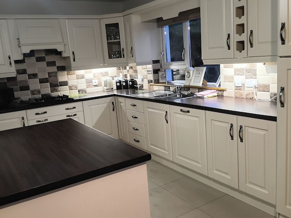 A modern kitchen with white cabinetry, a black countertop, and a window above the sink.