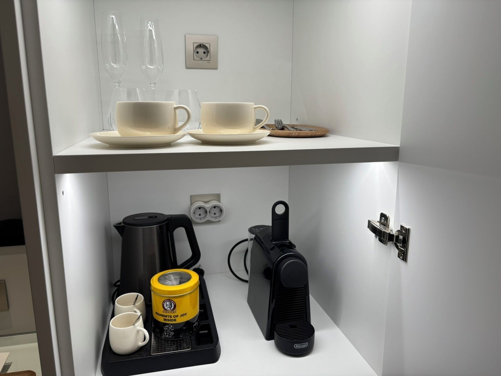 Una kitchenette con cafetera, hervidor y tostadora sobre la encimera.