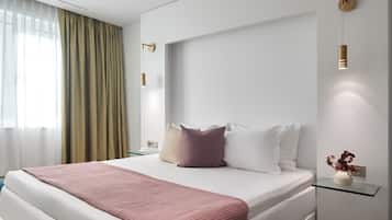 Une chambre d’hôtel moderne avec un grand lit, une table de chevet ornée d’un vase et un luminaire fixé au mur.