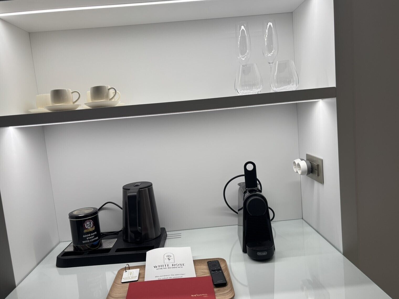 Angolo caffè con una macchina da caffè, una tazza e un telecomando su un tavolo.
