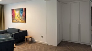 A modern living room with a sofa, a small wooden stool, and a painting on the wall. - WHITE ROSE ATHENS RESIDENCE (Athens)