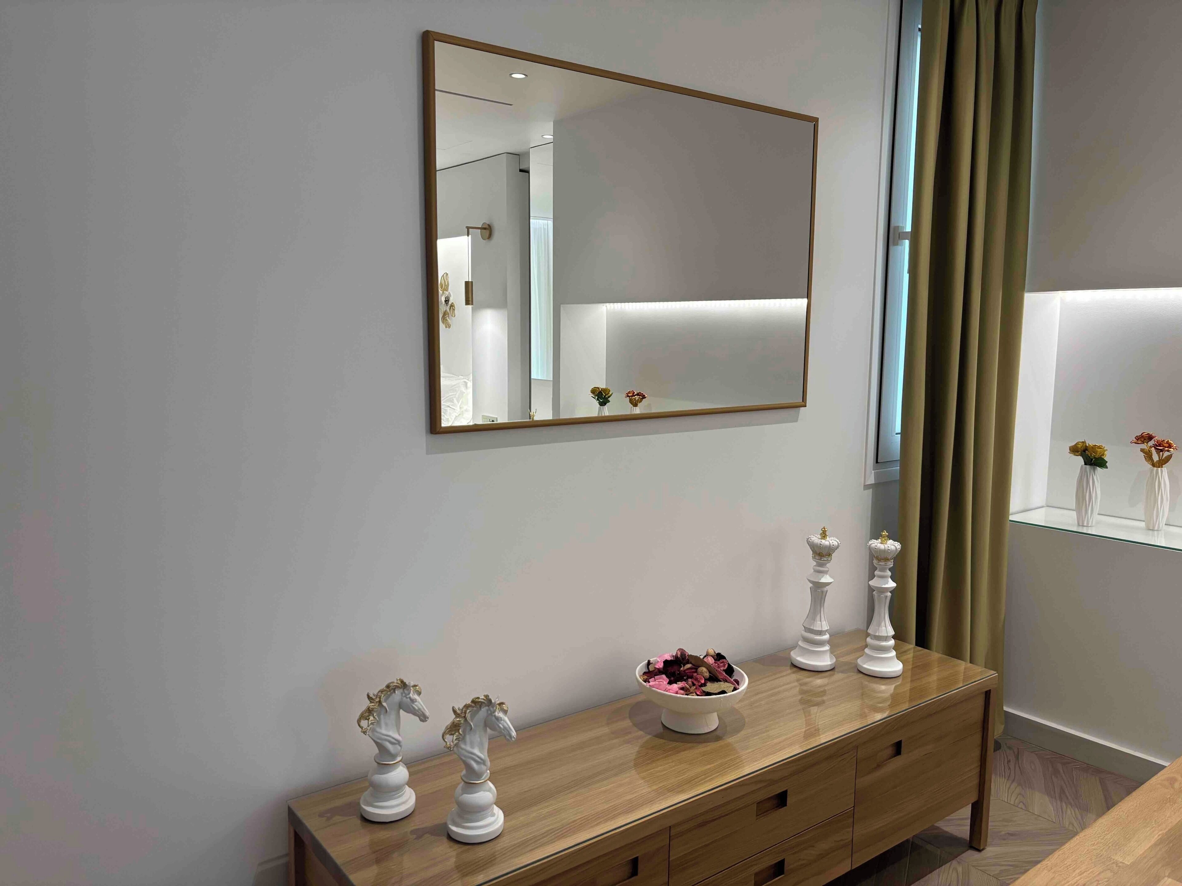 Un bagno moderno con un ampio specchio, un mobile lavabo con un cestino di articoli da toilette e un armadietto in vetro con oggetti decorativi.