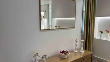 Un bagno moderno con un ampio specchio, un mobile lavabo con un cestino di articoli da toilette e un armadietto in vetro con oggetti decorativi.