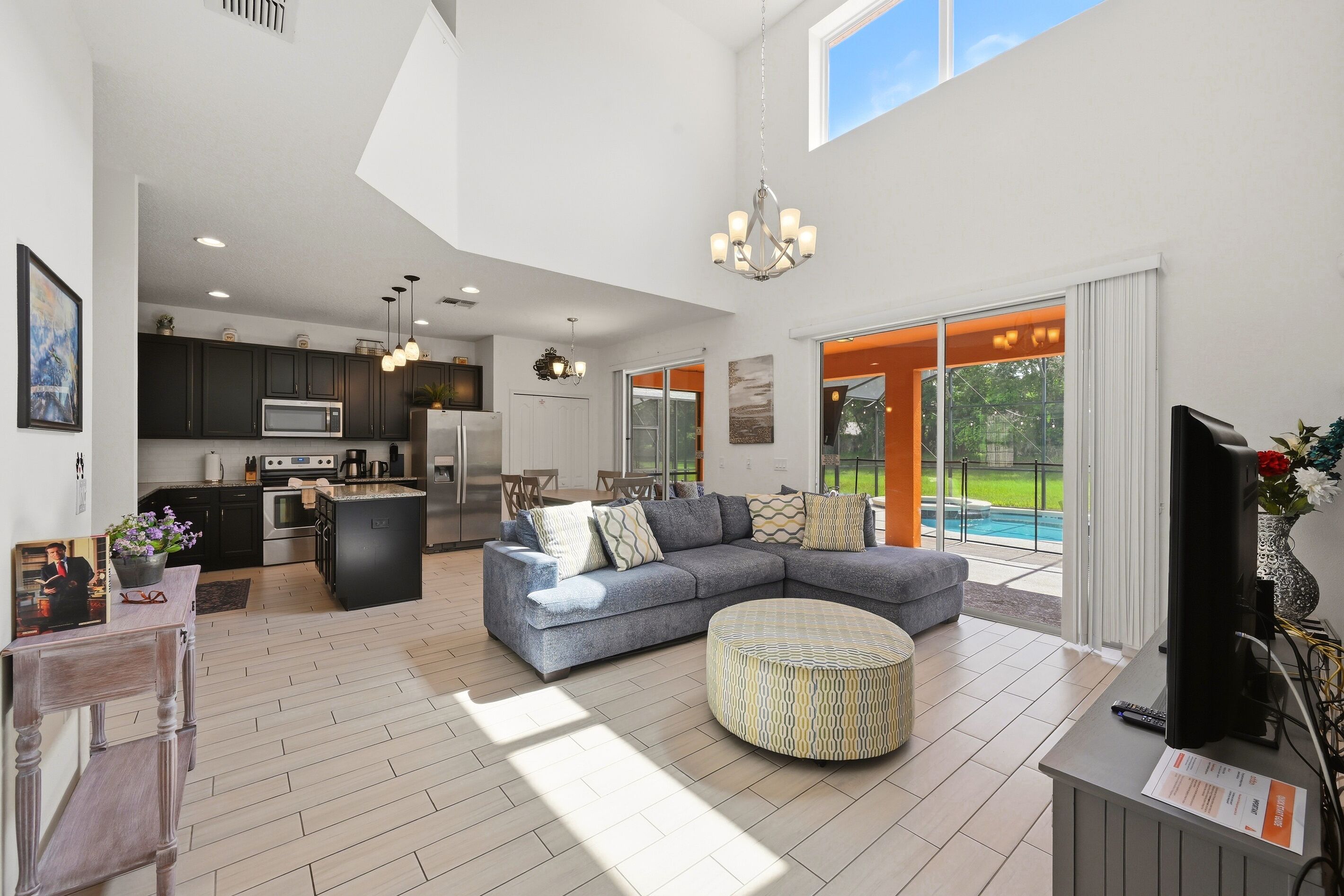 A spacious living area with a large sectional sofa, a round ottoman, and a flat-screen TV.