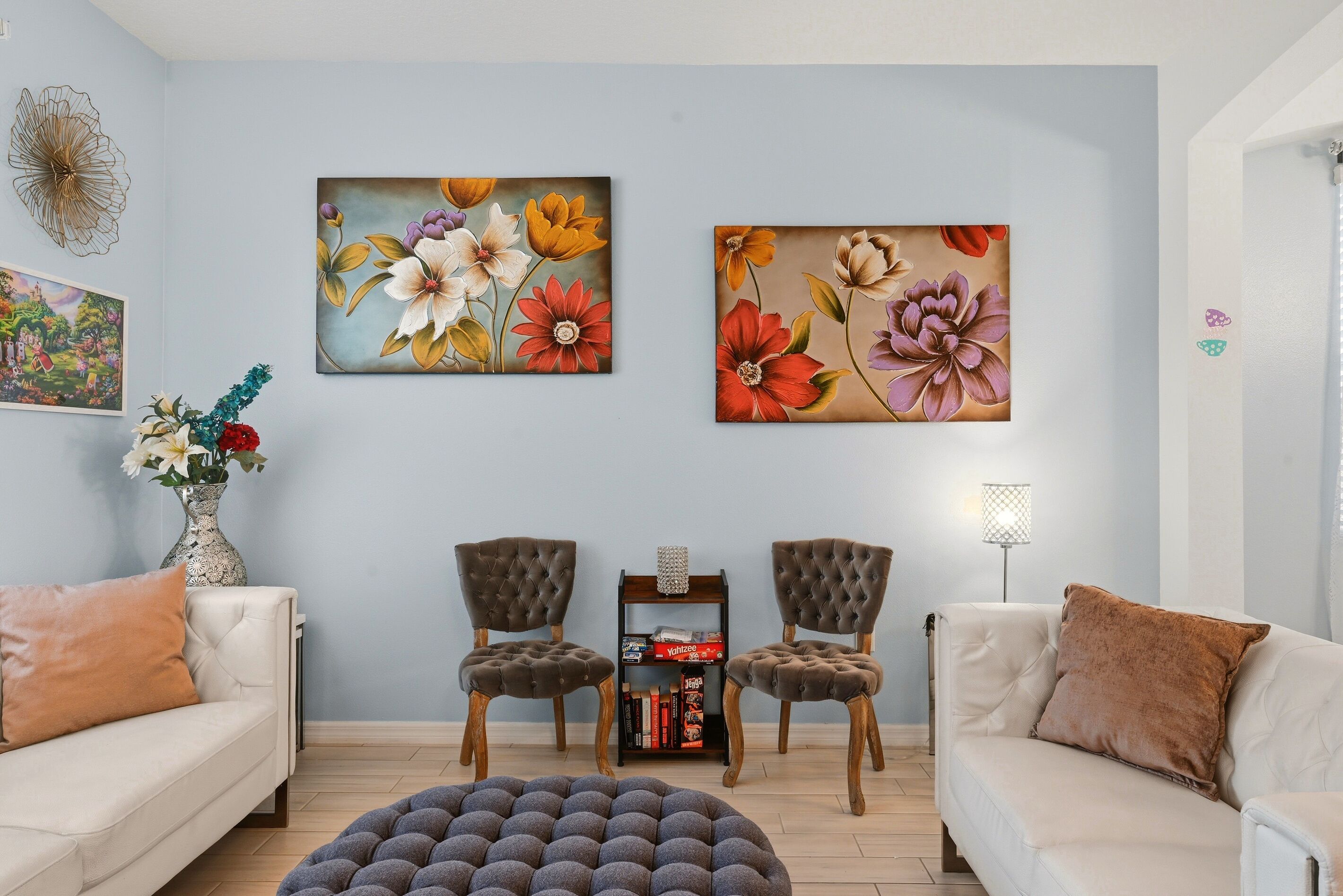 A living room with two sofas, a coffee table, two armchairs, and two paintings on the wall.