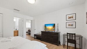 A bedroom with a bed, a TV on a dresser, a chair, and a desk. - Modern 6BRPoolVilla w/HotTub &GameRoom Near Disney (Kissimmee)
