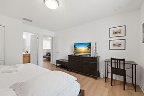 A bedroom with a bed, a TV on a dresser, a chair, and a desk. - Modern 6BRPoolVilla w/HotTub &GameRoom Near Disney (Kissimmee)