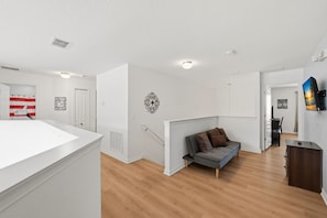 A modern living room with a grey sofa, a white ceiling, and a wooden floor. - Modern 6BRPoolVilla w/HotTub &GameRoom Near Disney (Kissimmee)