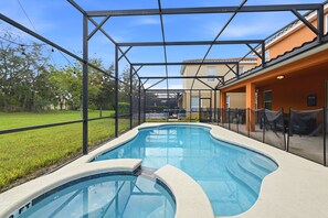 Uma piscina com uma característica de água azul cristalina, rodeada por uma área coberta com estrutura de metal e barreira de vidro.