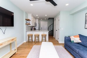 Un espacio habitable moderno con cocina, comedor y zona de estar con sofá y televisión.