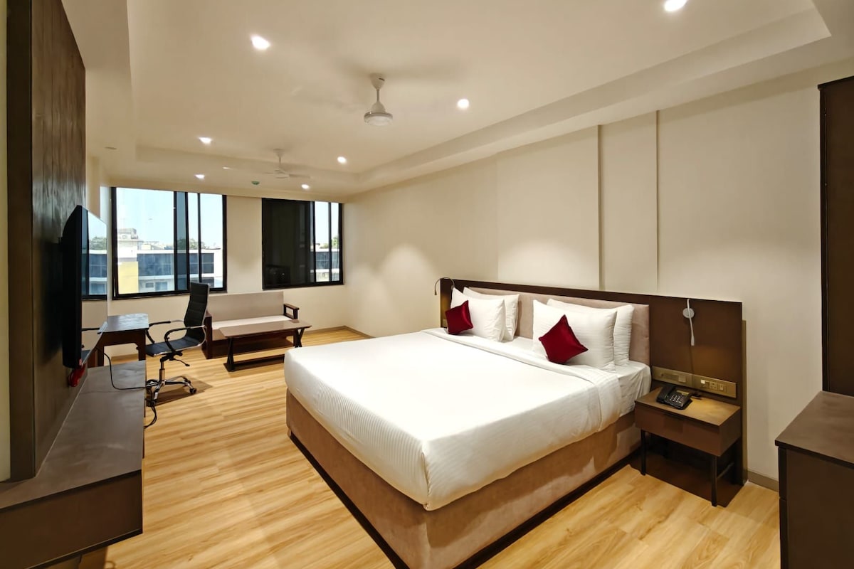 Un dormitorio moderno con una cama grande, un escritorio, una silla y un televisor.
