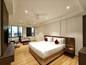 Un dormitorio moderno con una cama grande, un escritorio, una silla y un televisor.