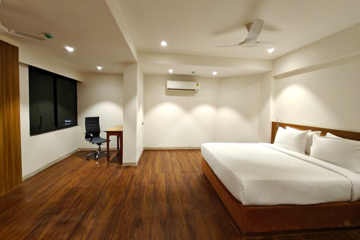 Habitación de hotel con cama, escritorio, silla y ventana.