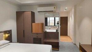 Ein Hotelzimmer mit Bett, Schrank, Spiegel und einer kleinen Sitzecke.