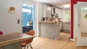 Una cucina moderna con isola centrale, mobili bianchi e una parete d'accento rossa.