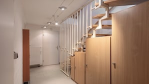 Un corridoio con armadietti in legno, un termosifone e una porta.