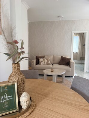 A living room with a sofa, a coffee table, and a decorative vase with plants.