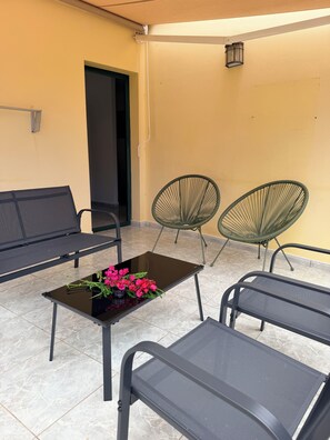 A seating area with a bench, two chairs, and a table with flowers. - Ornia Apartments I Champagne Apartment I Private Balcony with Ocean View (Lomo Quiebre)