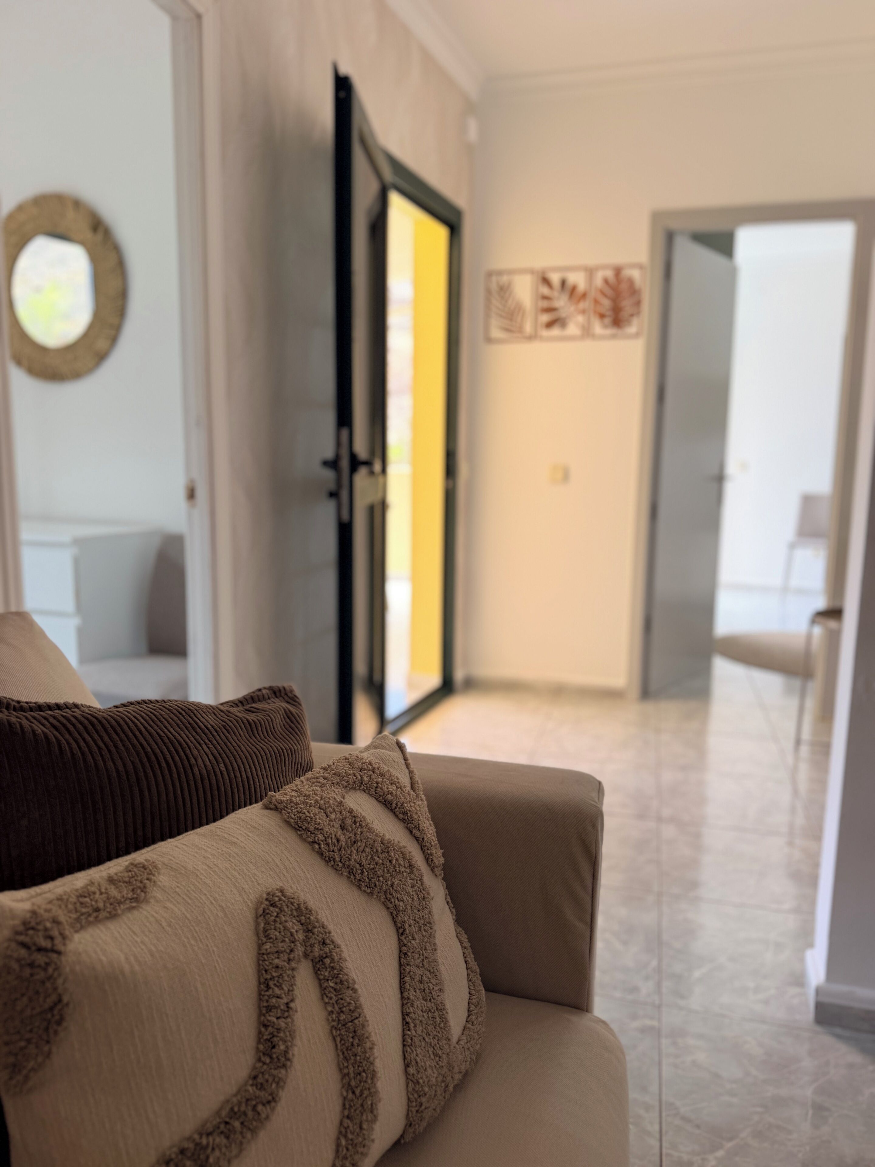 A modern living room with a sofa, a door leading to another room, and a hallway.