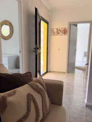 A modern living room with a sofa, a door leading to another room, and a hallway. - Ornia Apartments I Champagne Apartment I Private Balcony with Ocean View (Lomo Quiebre)