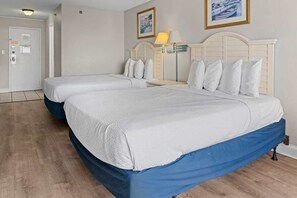 Ein Hotelzimmer mit zwei Betten, Holzboden, weißer Tür und einer Lampe.