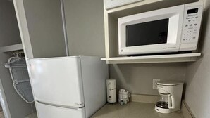 A compact kitchenette with a white refrigerator, a microwave, a coffee maker, and a small sink. - Sea Mist 51112 Ocean View Vacation Rental (Myrtle Beach)