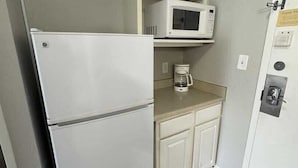 A compact kitchenette with a white refrigerator, microwave, and a coffee maker on the countertop. - Sea Mist 51112 Ocean View Vacation Rental (Myrtle Beach)